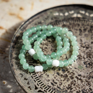 Stack of Green Aventurine crystal bracelets on a metal tray
