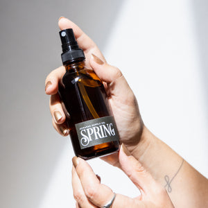 hand holding spring room spray in amber bottle