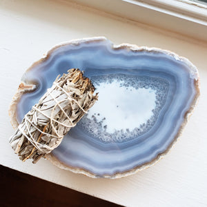 Top view of a small Agate tray with alternating light and dark bands and a sage smudge stick