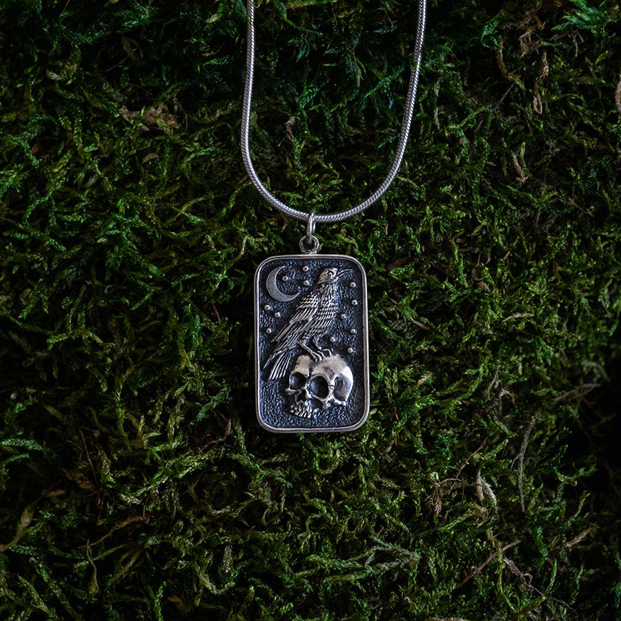 Silver skull and raven charm