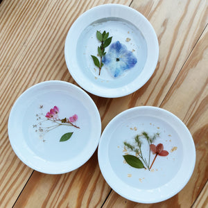 3 pressed flower trinket dishes on a wooden table