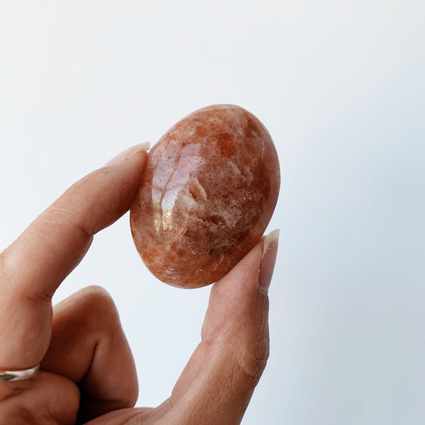 Hand holding a sunstone palm stone