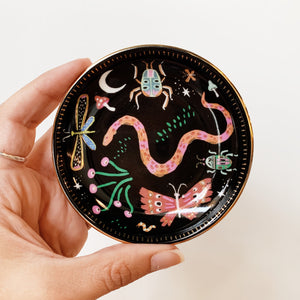 Ceramic dish painted black with colorful bugs, plants, and mushrooms