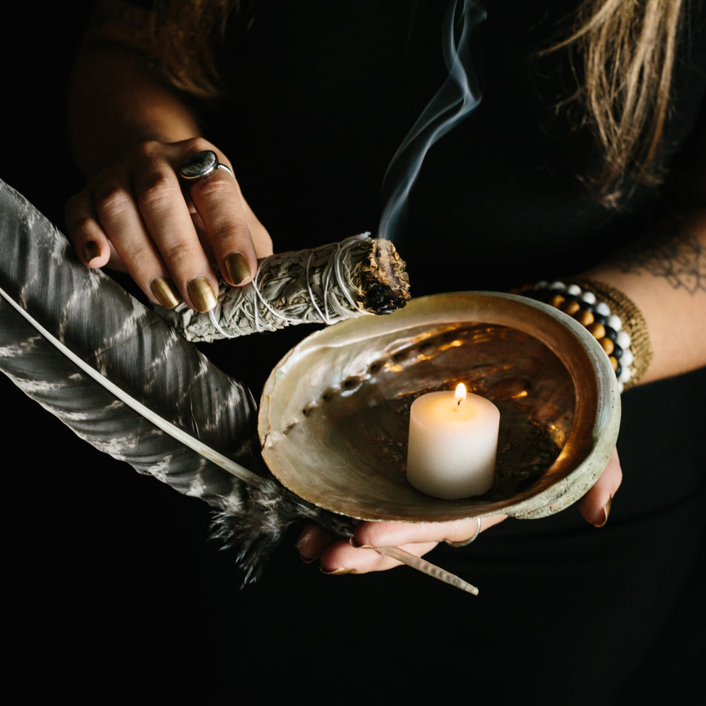 Cleansing bundle with sage, turkey feather, candle, and abalone shell